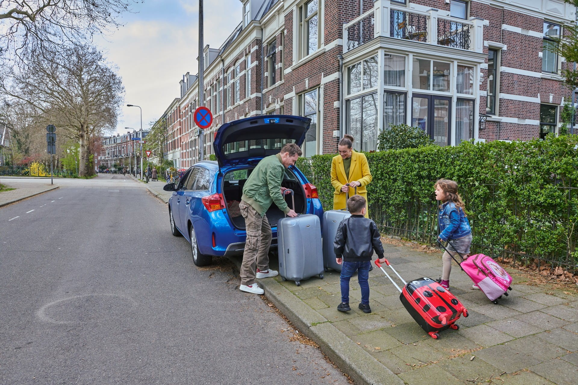 Gezin met twee kinderen laadt auto in met koffers