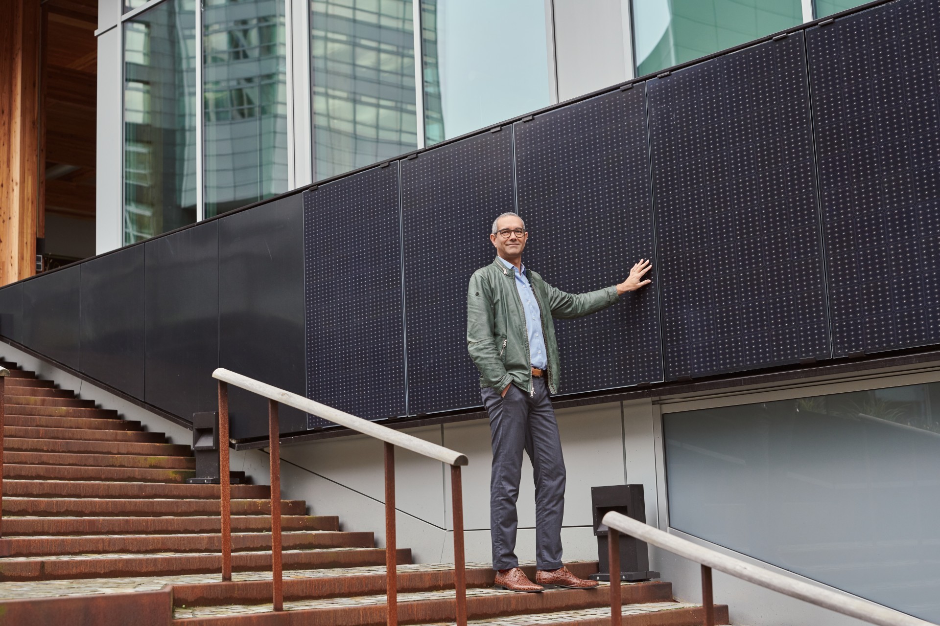 Man kijkt en raakt zonnepanelen aan die aan de zijkant van een pand zijn aangebracht