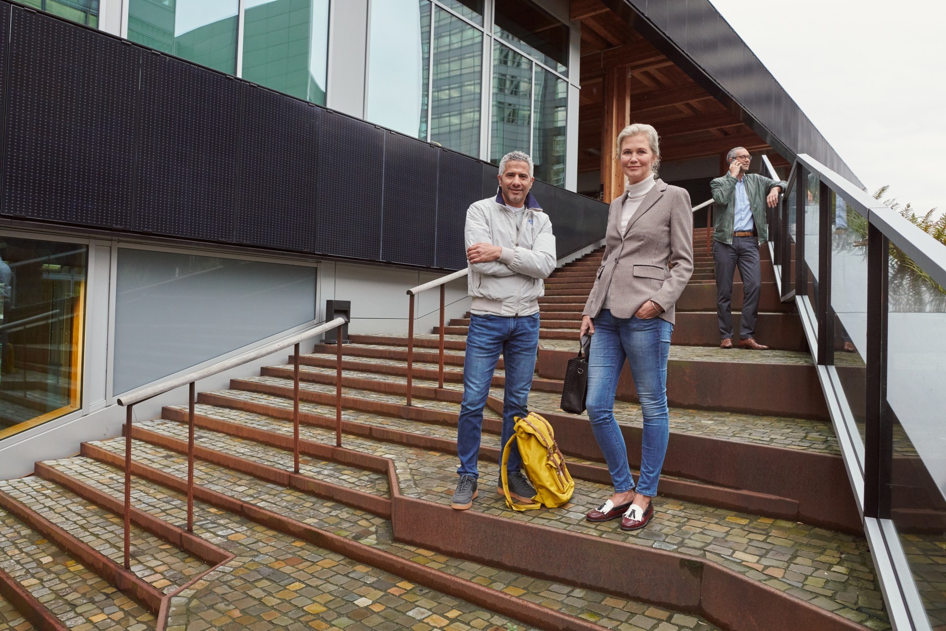 Drie mensen staan op trap bij een groen bedrijfspand