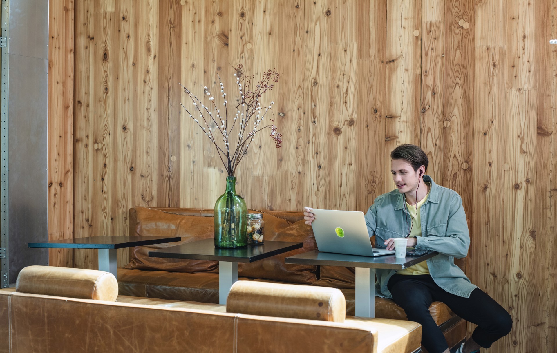 Man kijkt met oortjes in naar zijn laptop