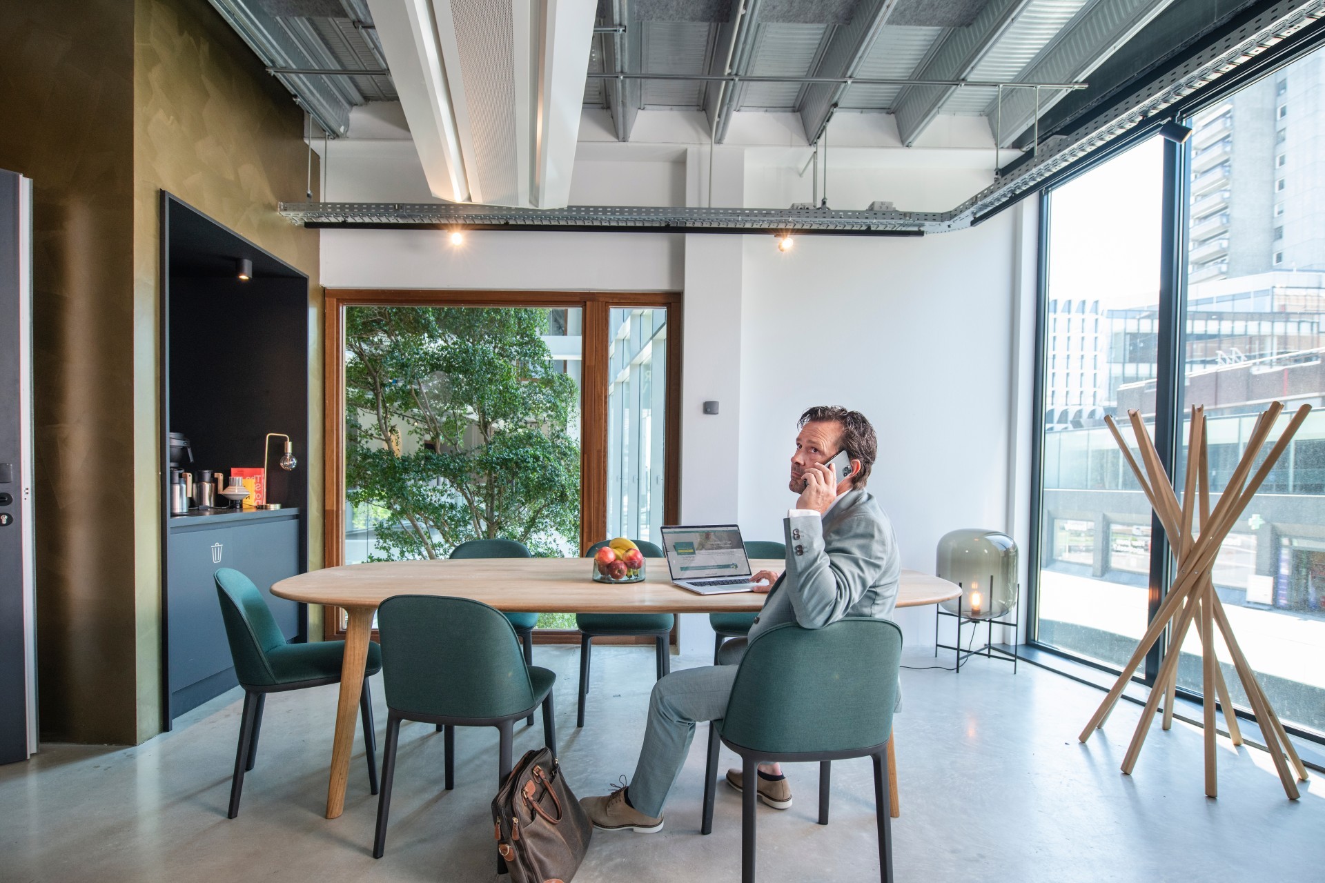 Man in pak telefoneert terwijl hij website van ABN AMRO op de laptop bekijkt