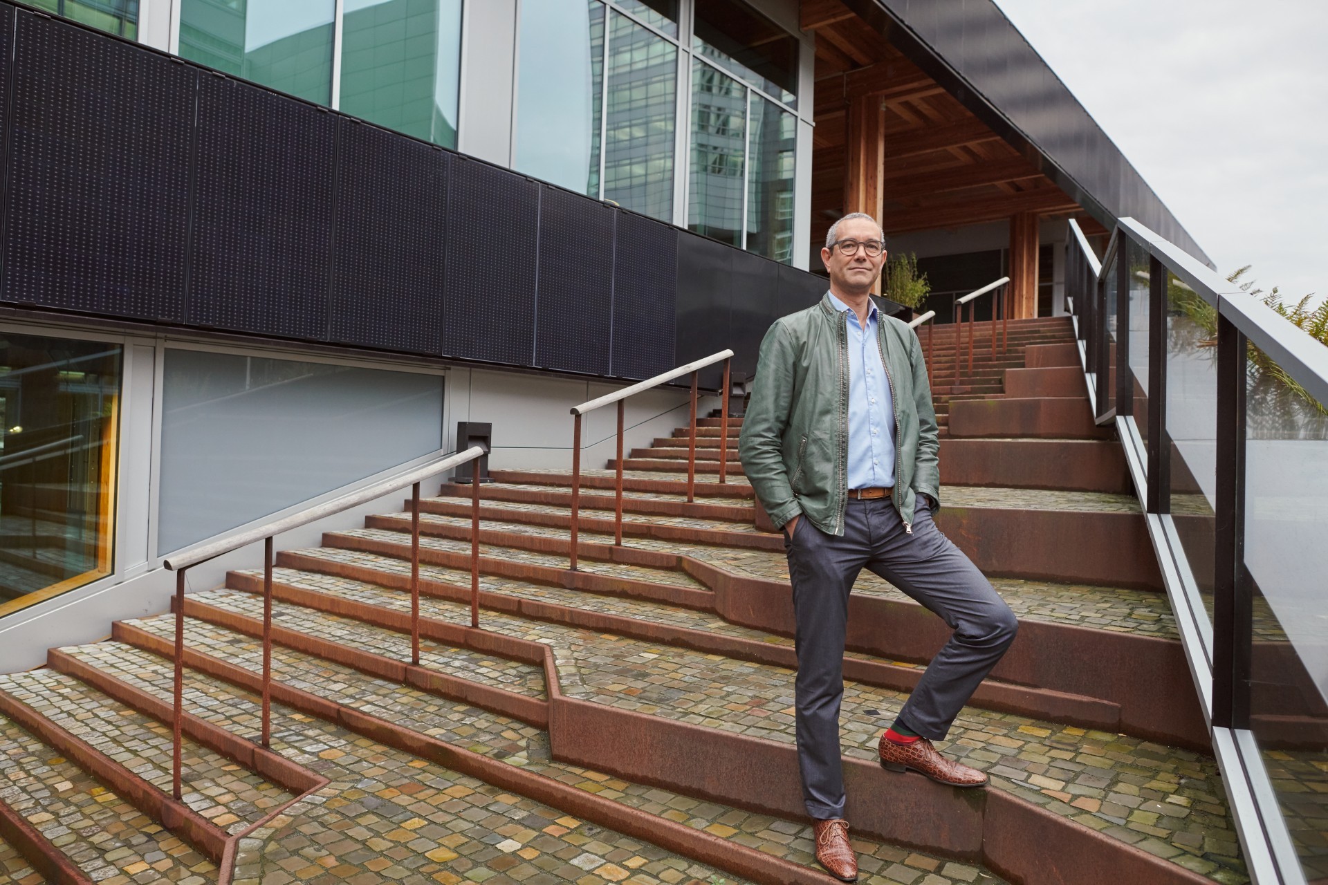Man staat op trap voor zijn gebouw met zonnepanelen