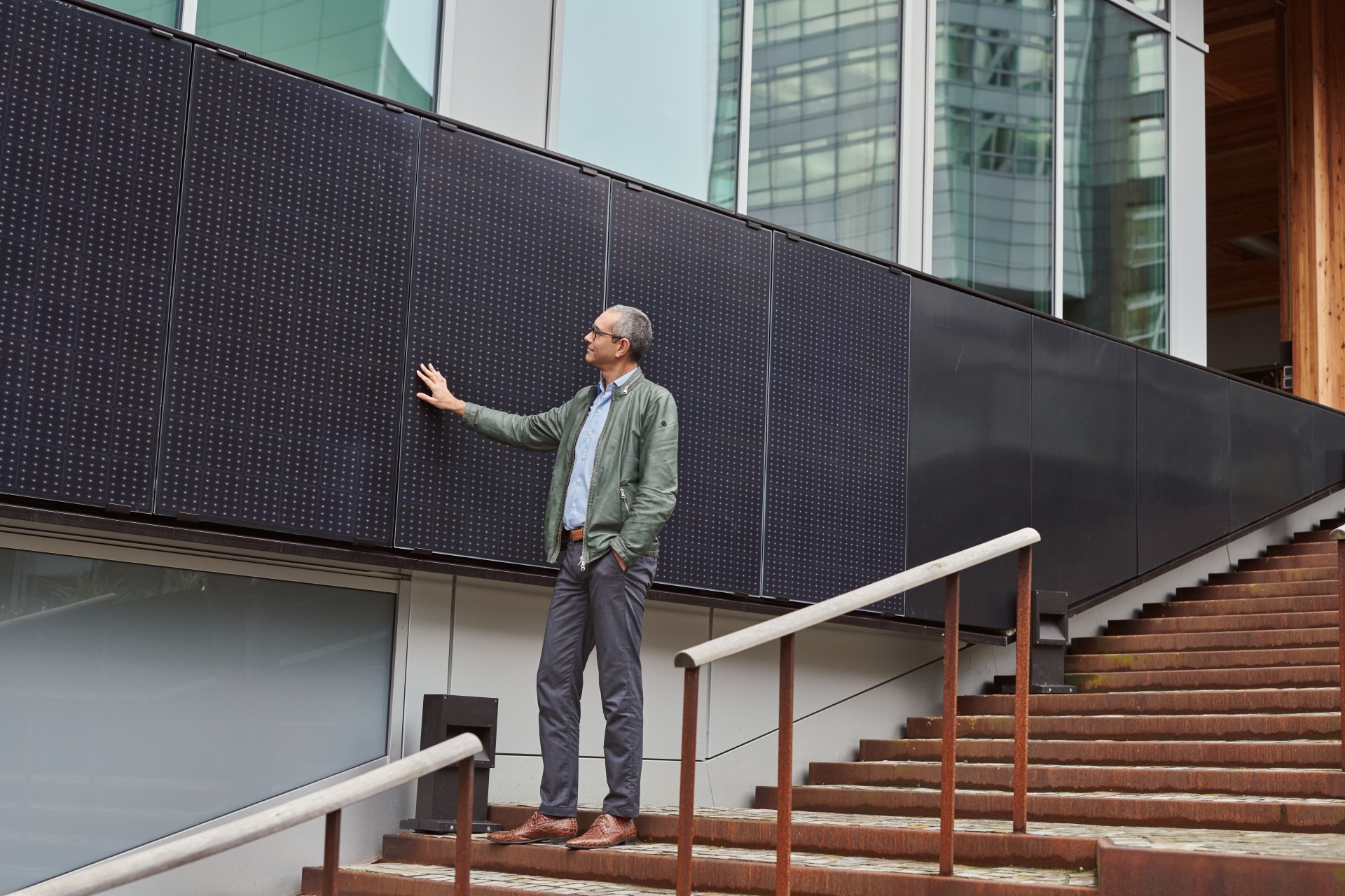 Man kijkt en raakt zonnepanelen aan die aan de zijkant van een bedrijfpand zijn aangebracht