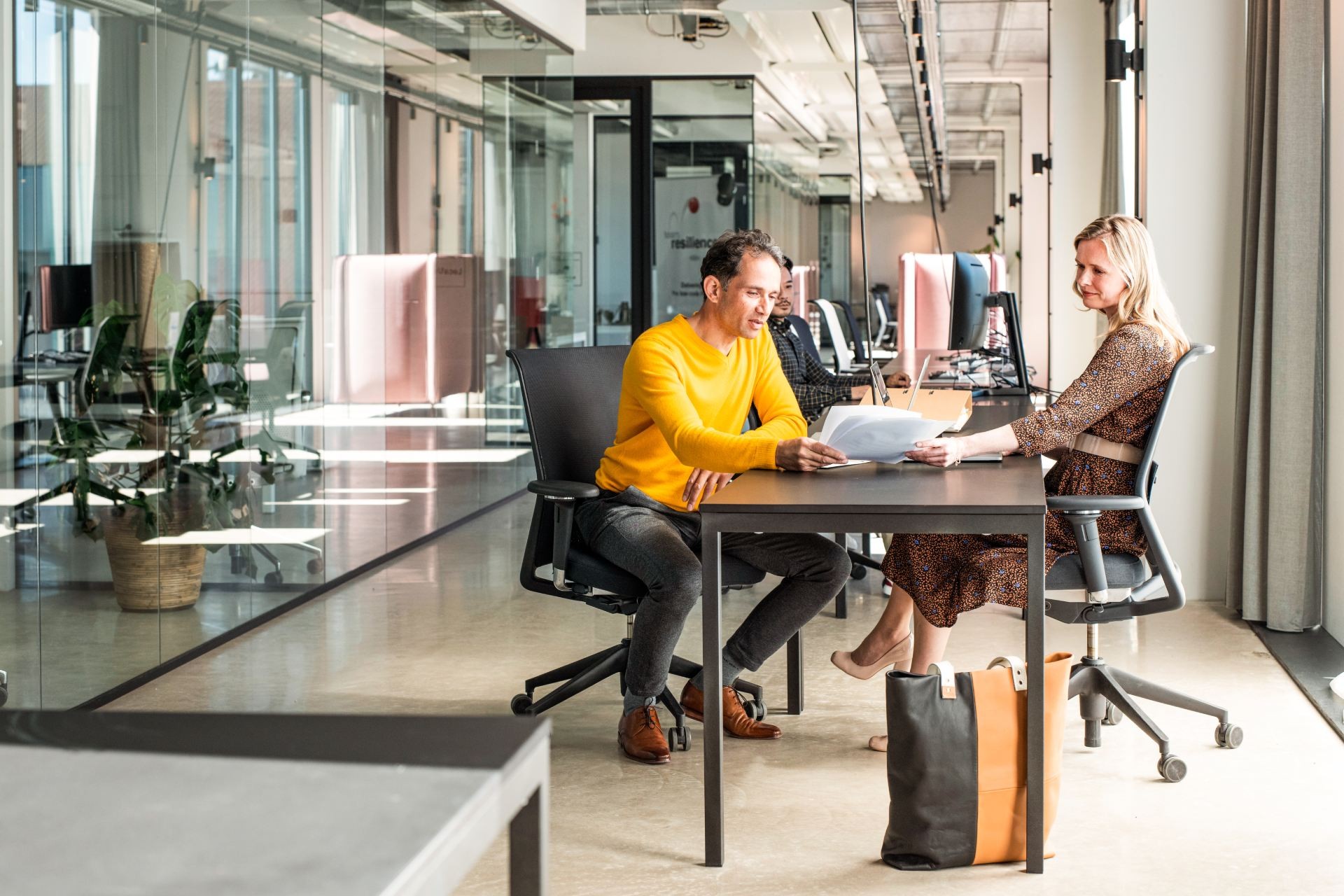 Een man en vrouw zitten achter een bureau en bekijken samen een papieren document